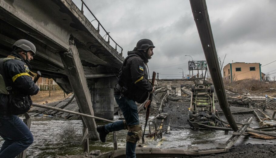 Ουκρανοί στρατιώτες περνούν δίπλα από κατεστραμμένη γέφυρα στο Κίεβο ©EPA/ROMAN PILIPEY