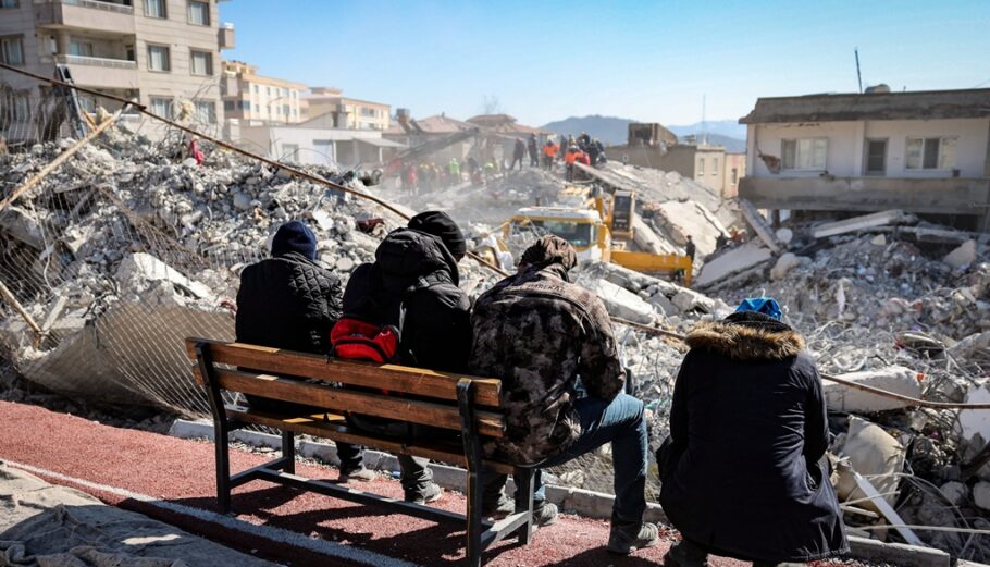Άνθρωποι παρακολουθούν τους διασώστες που αναζητούν επιζώντες στα ερείπια ενός κτιρίου που κατέρρευσε μετά από σεισμό στην Τουρκία @ EPA/JOAO RELVAS